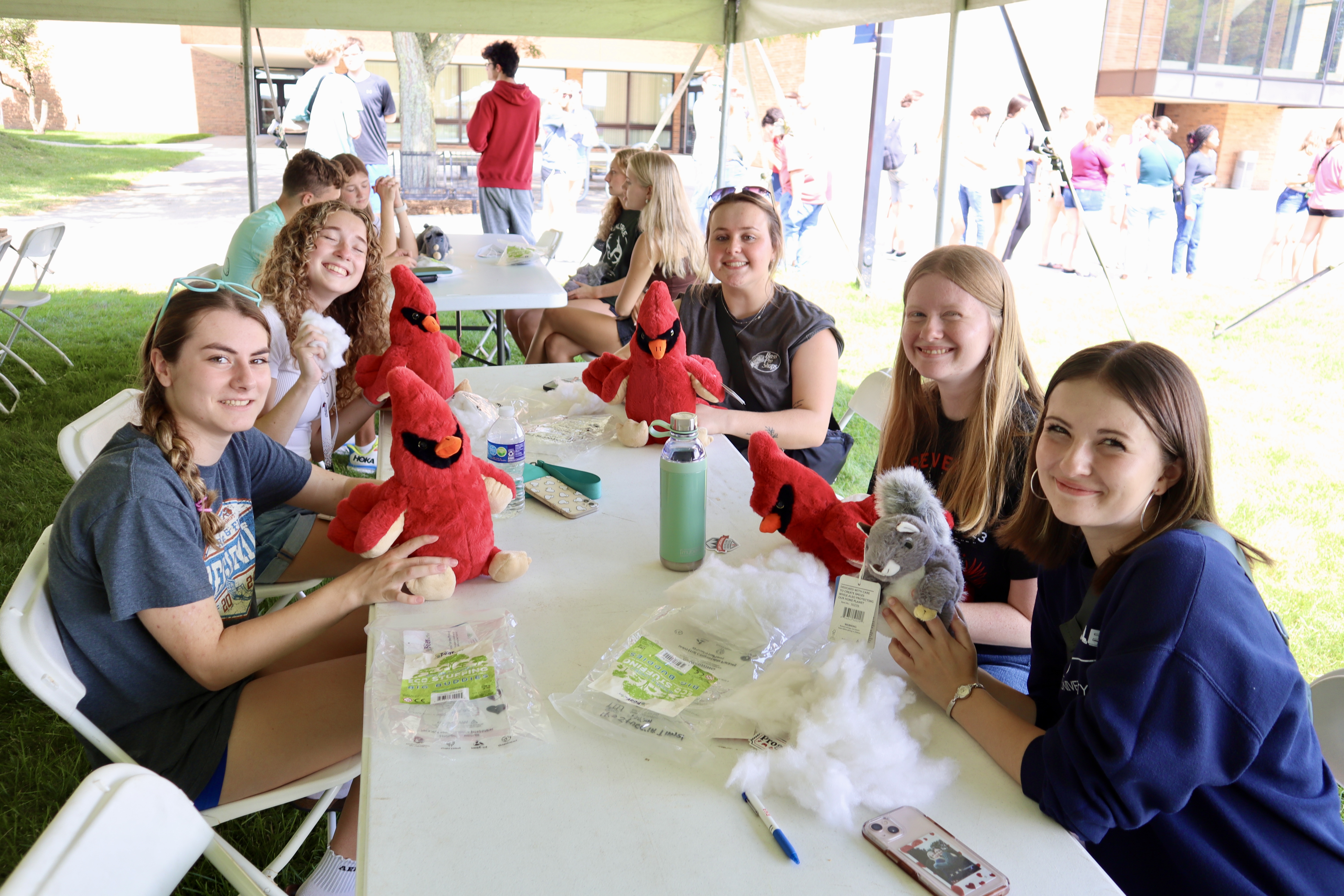 Students seated at a table while stuffing their red Cardinal plushies at the Welcome Weekend Stuff-A-Plush event.